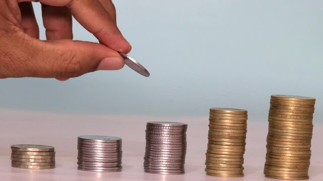 Stacks of coin arranged in a graphical manner for accounting, budget, investing, planning. Used fingure to add one by one in a stacked manner.