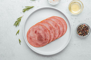 Sliced sausage on white plate with herbs and spices