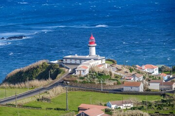 Farol da Ponta do Topo Lighthouse Overlooking the Atlantic, Sao Jorge, Azores. Scenic view of the iconic red and white lighthouse perched on the cliffside, with the vast blue ocean