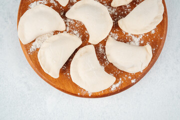 Homemade dumplings arranged on a wooden board ready for cooking in the kitchen