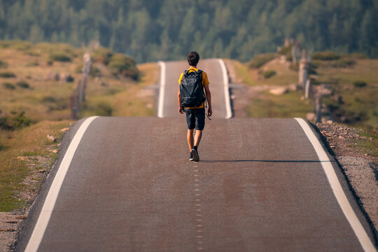 Adventurer Travels Alone on Scenic Open Road with Backpack