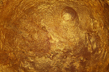Closeup of golden fluid metallic acrylic paint textured background