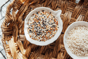 Different types of  seeds displayed in bowls on a woven tray