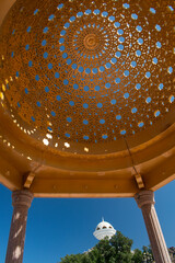 Obraz premium Muscat, Oman, 03-10-2025: the Riyam Censer Muscat, iconic monument shaped like a traditional incense burner and perched atop a hill in Riyam Park, seen from under the vault of a parasol structure