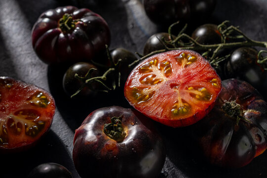 Fresh black tomatoes with vibrant red interiors in shadow - Powered by Adobe