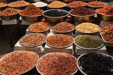 Assorted nuts and dried fruits displayed in large metal bowls at open-air Turkish market