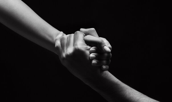 Strong connection. Unrecognizable woman hand helping man to stand up on background, black and white