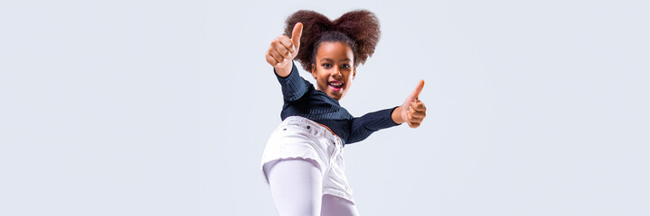 Happy young girl in stylish outfit showing thumbs up. Human gestures concept. African american little girl in showing thumb up