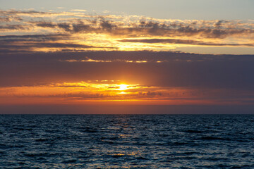 Fototapeta premium The sky is a beautiful orange color as the sun sets over the ocean