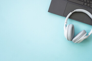 Laptop and wireless headphones on blue background.