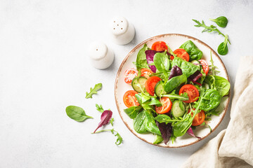 Salad from green leaves and vegetables on white.