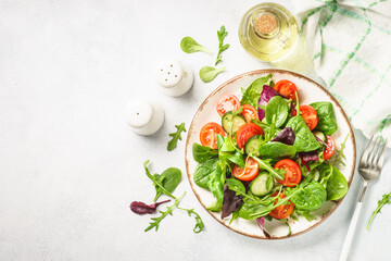 Salad from green leaves and vegetables on white.
