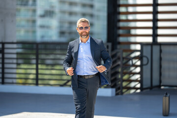 Successful businessman walking outdoors. Confident businessman. Success business. Mature businessman in suit. Handsome corporate leader. Rich businessman in urban setting. Elegant business n leader.