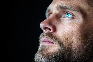 tight crop of a man in deep thought, intense eyes, black background