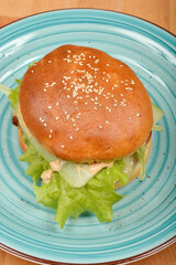 A delicious homemade burger with fresh lettuce and sauce is served on a light blue plate