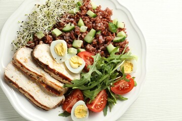 Delicious salad with brown rice on white wooden table, top view