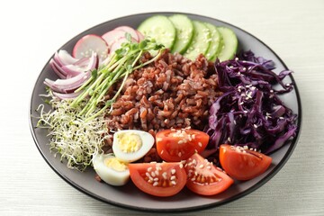 Tasty salad with brown rice on white wooden table, closeup