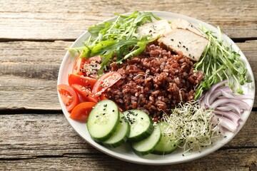 Delicious salad with brown rice on wooden table, closeup