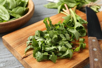 Cut fresh sorrel leaves and knife on grey wooden table, closeup