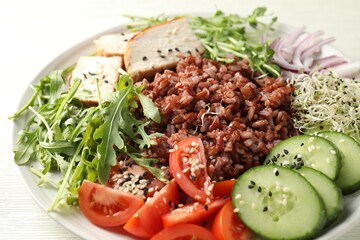 Delicious salad with brown rice on white wooden table, closeup