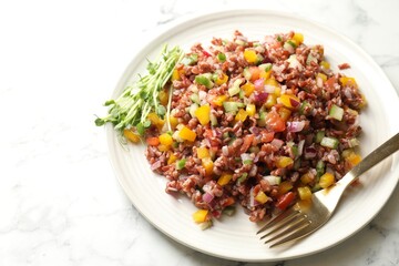 Tasty salad with brown rice on white marble table, closeup