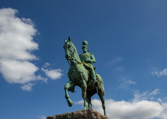 Equestrian statue of a historical figure against a bright blue sky with scattered clouds. Classic monument symbolizing leadership, history, and heritage.