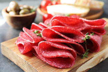 Slices of delicious sausage with thyme served on grey table, closeup