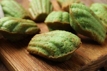Tasty matcha madeleine cakes on wooden board, closeup