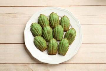 Tasty matcha madeleine cakes on light wooden table, top view