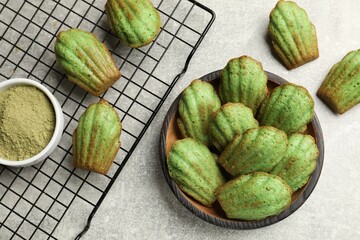 Tasty madeleine cakes and matcha powder on light table, flat lay