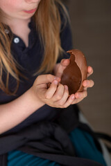 Young caucasian child enjoying chocolate egg treat indoors