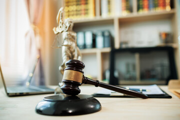 Lady Justice, scales, and a gavel placed on a judge’s desk represent fairness and integrity in...