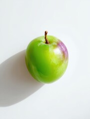 Studio shot of a single green jujube fruit on white background with natural lighting and shadow from above