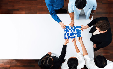 A dynamic office scene showcasing a diverse team collaboratively working on a blue puzzle piece,...