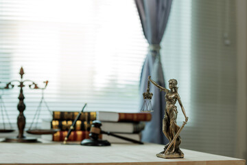 Lady Justice, scales, and a gavel placed on a judge’s desk represent fairness and integrity in...