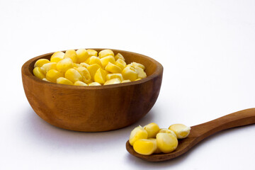 A wooden bowl with corn kernels, isolated on white background.