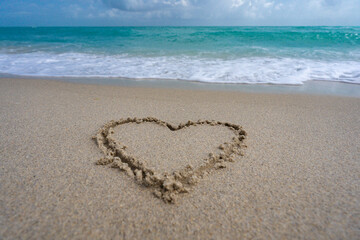 Heart drawn in sand. Waves forming a heart shape sign. Love on beach. Romantic summer. Heart made of sand. Love and ocean waves.