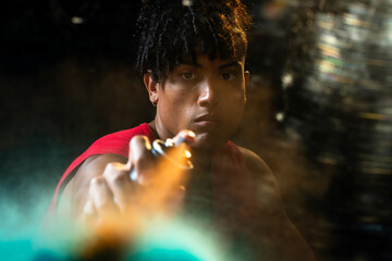 Man in sleeveless red top spraying mist in dim room, with spray can and disco ball