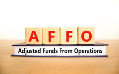 AFFO symbol. Concept word AFFO Adjusted Funds From Operations on beautiful wooden blocks and book....