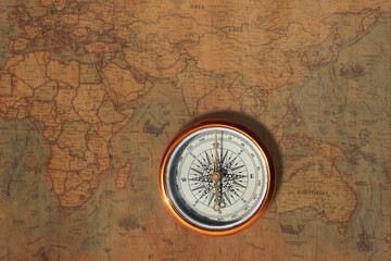 Classic round compass on background of old vintage map of world