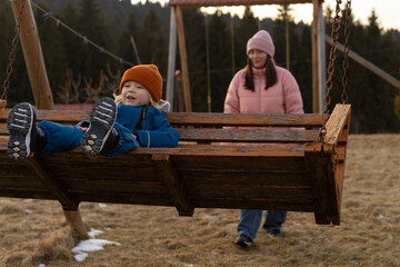 A woman swings her son on a swing in the yard