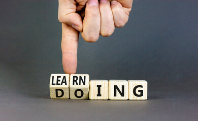 Doing or learning symbol. Businessman turns wooden cubes and changes the word Doing to Learning ....