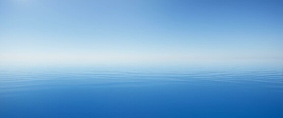 The serene minimalism of a calm blue ocean merges flawlessly with a clear, pale blue sky, creating infinite peace.