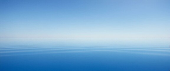A tranquil, minimalist seascape: perfectly still blue waters reflect the soft gradient of a clear, cloudless sky.
