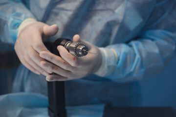 Close-up of a veterinary surgeon in surgical gloves and gown skillfully holding a specialized drill...