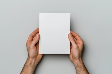A person is holding a white piece of paper. The paper is blank and has no writing on it