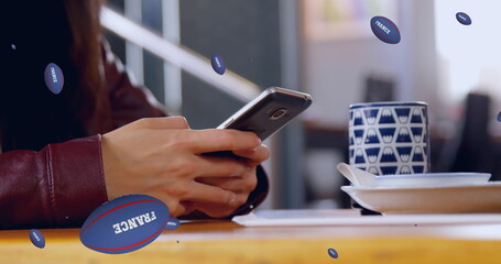 Image of rugby balls with france text falling over caucasian woman using smartphone