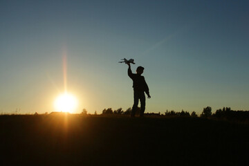 A little boy is playing outside with a toy airplane that he made himself. childhood