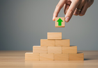 Hand Placing Green Arrow Block on Wooden Pyramid Structure Symbolizing Growth Success Progress Achievement Strategy Plan Business Development