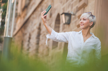 Trendy adult woman holding in hands smartphone and making selfie. adult woman using smart phone.